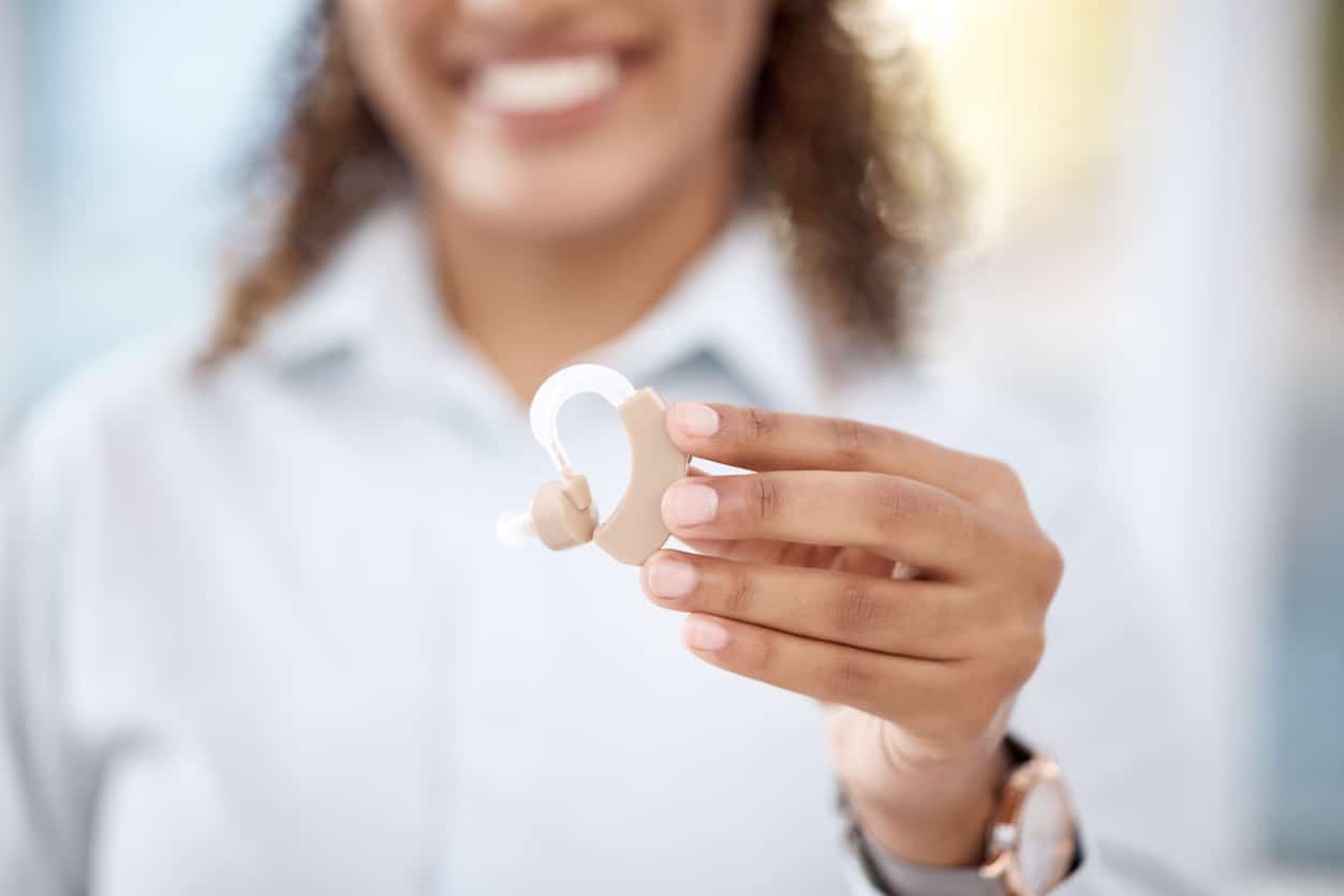 Close up photo of an audiologist holding up a hearing aid.