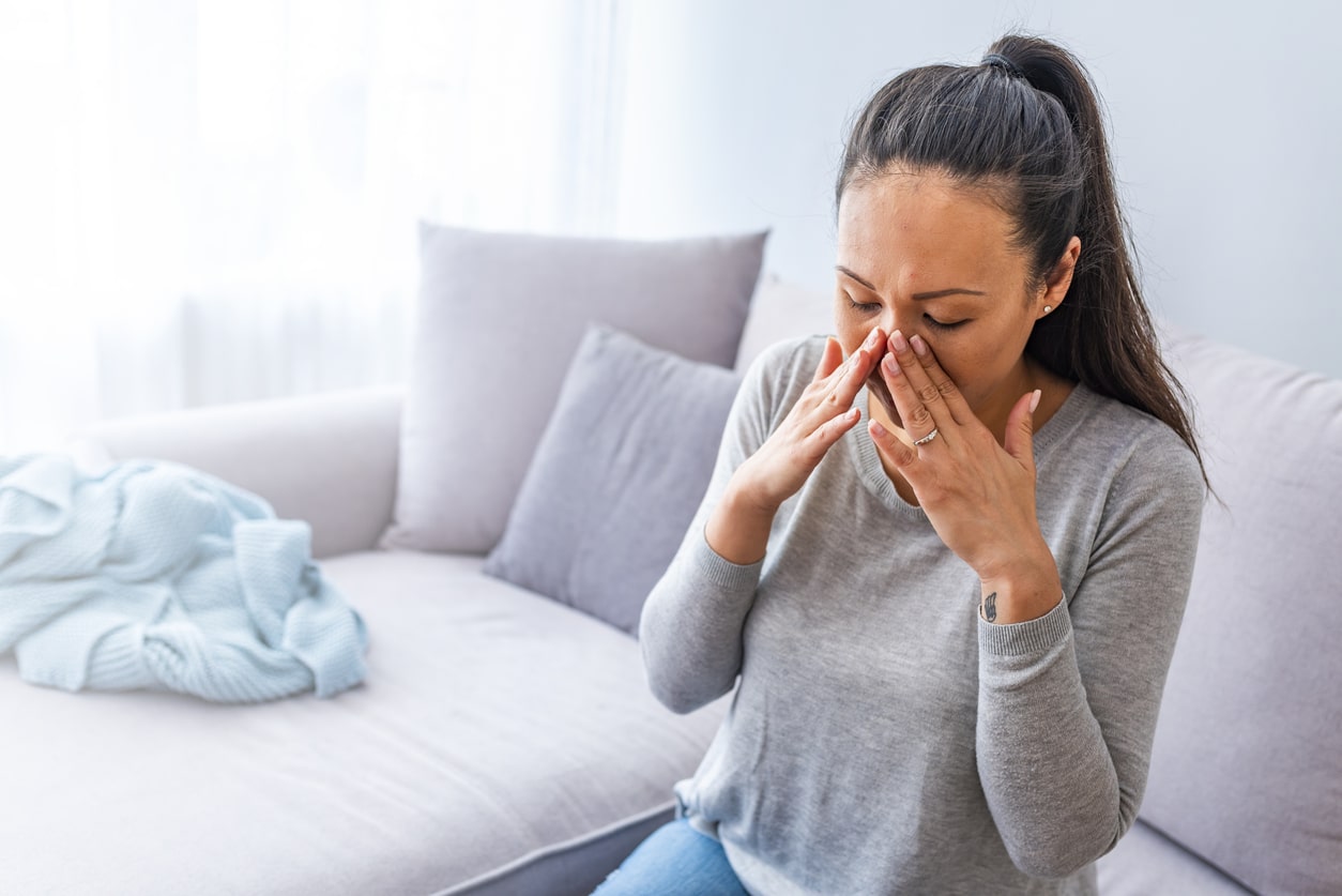 Woman with a sinus headache holding her nose.