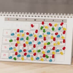 Calendar with lots of push pins, overbooked fully booked schedule c