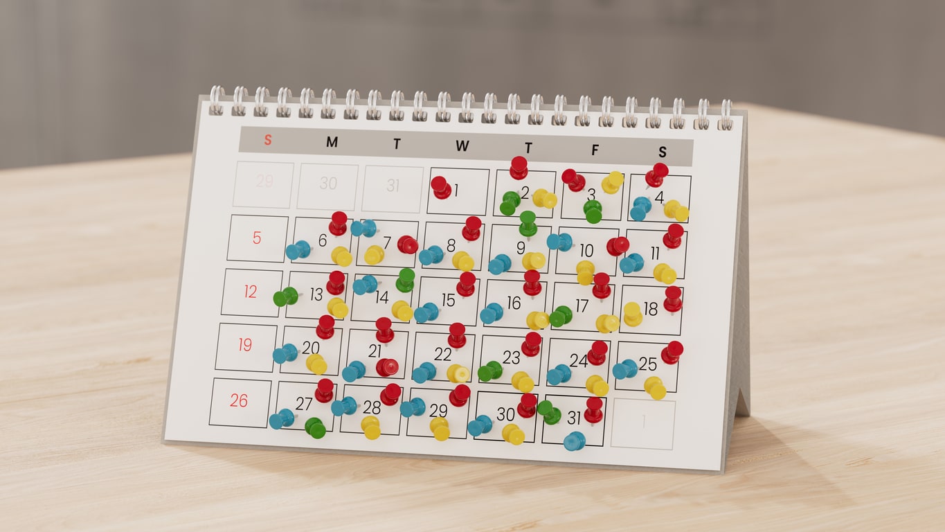Calendar with lots of push pins, overbooked fully booked schedule 