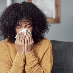 Woman with the flu blowing her nose into a tissue